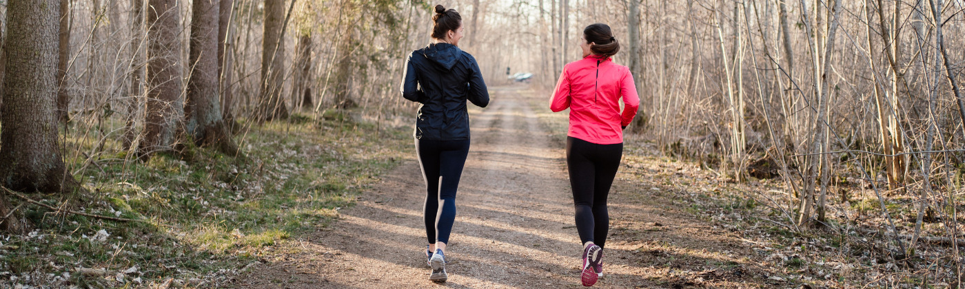 Two women running on a path through the woods