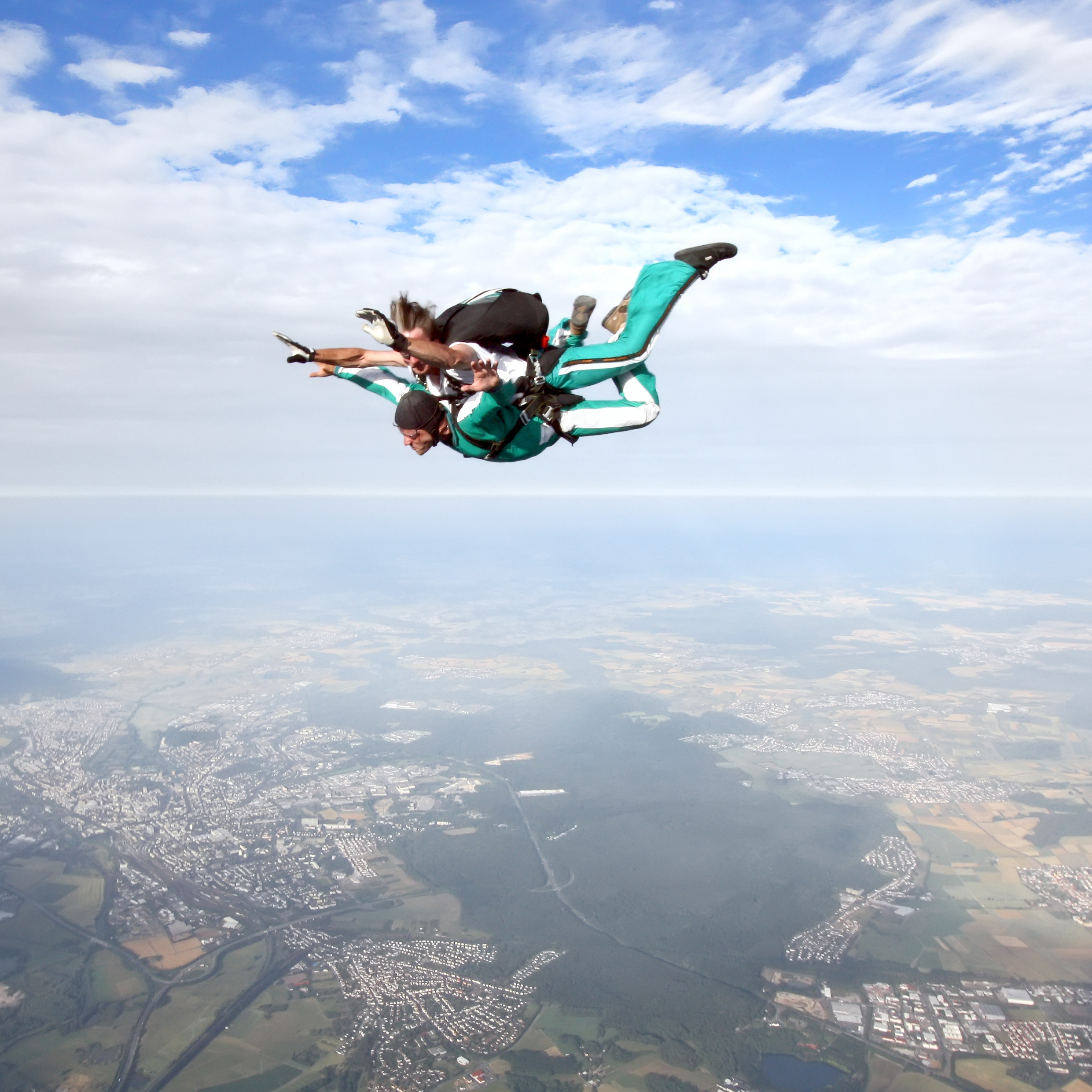 Two people strapped together in mid-air doing a tandem skydive.
