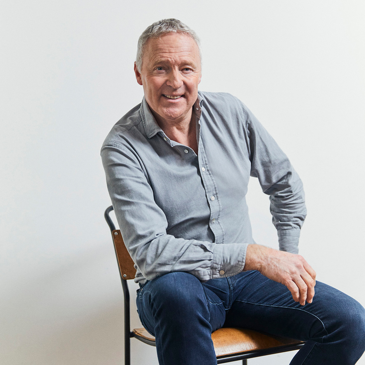 Rory Bremner sitting casually in a chair smiling at the camera