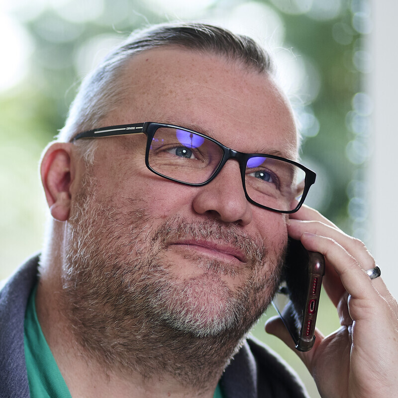 A man smiling while taking a phone call
