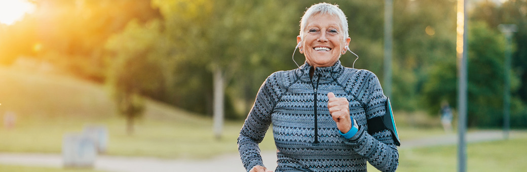 Woman with short grey hair with headphones in smiling and jogging