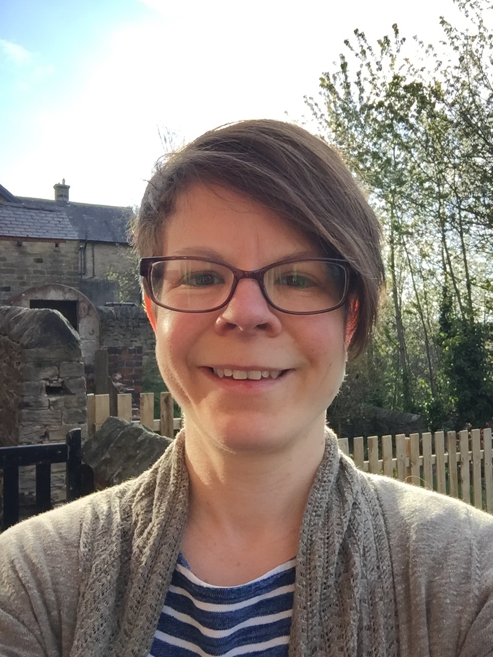 A white woman with short brown hair and glasses.