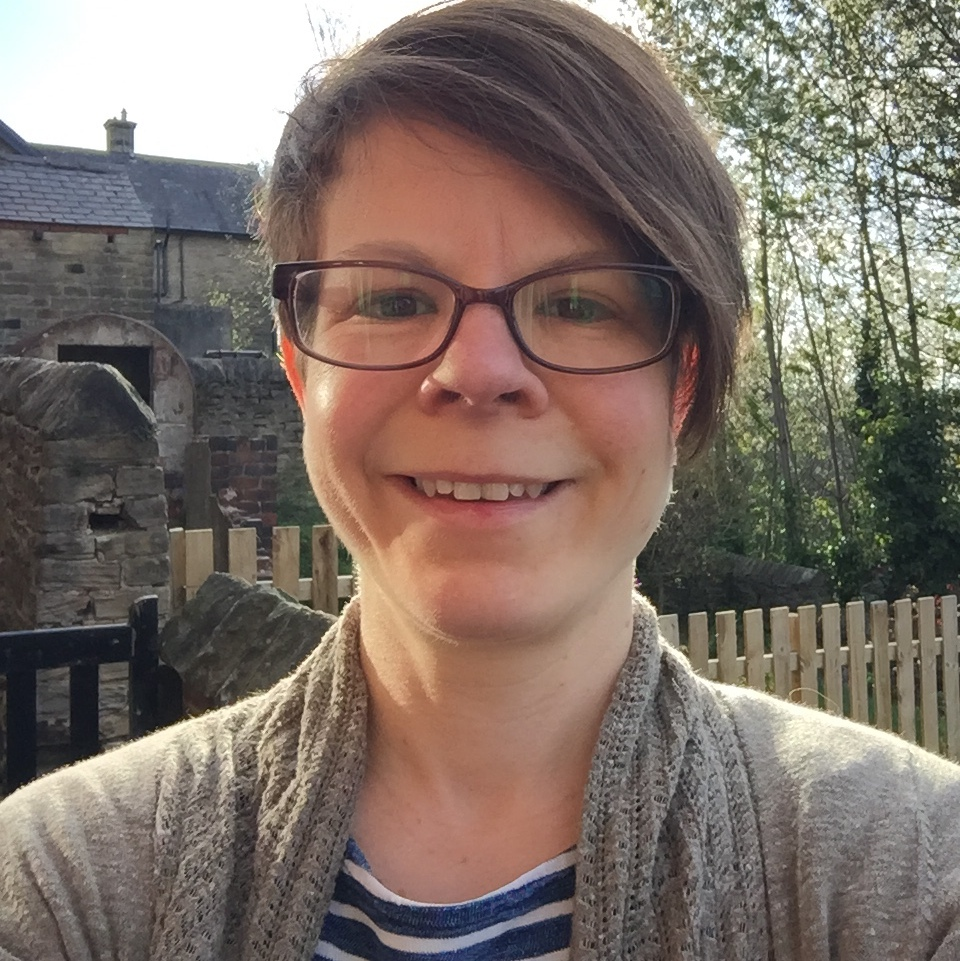 A white woman with short brown hair and glasses.
