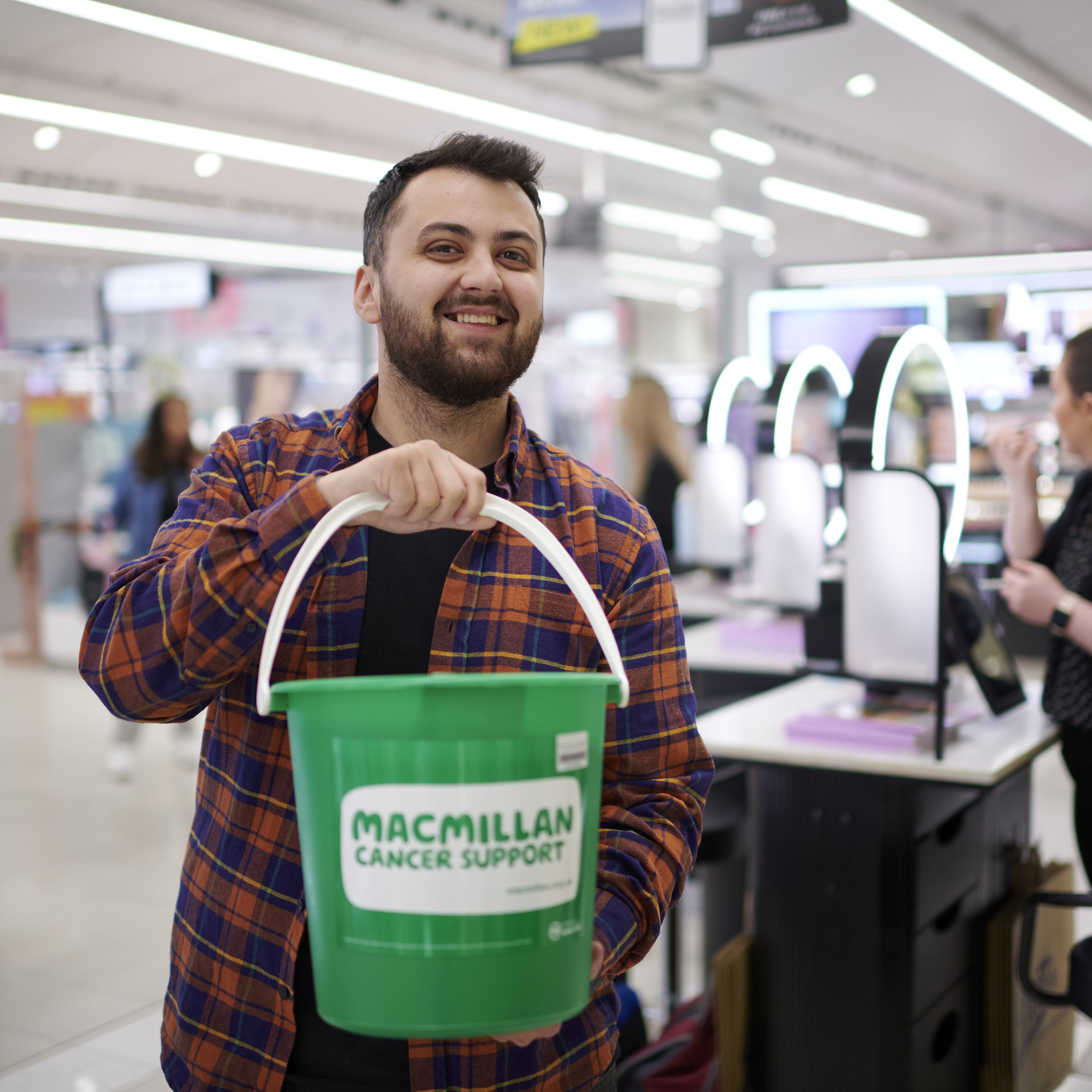 A man with a Macmillan bucket in a Boots store