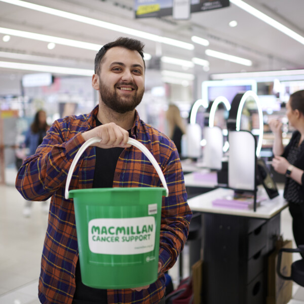 A man with a Macmillan bucket in a Boots store