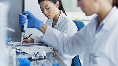 scientists in white lab coats working in a lab.