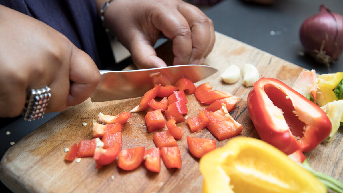 A close-up woman's hands chopping fresh vegetables