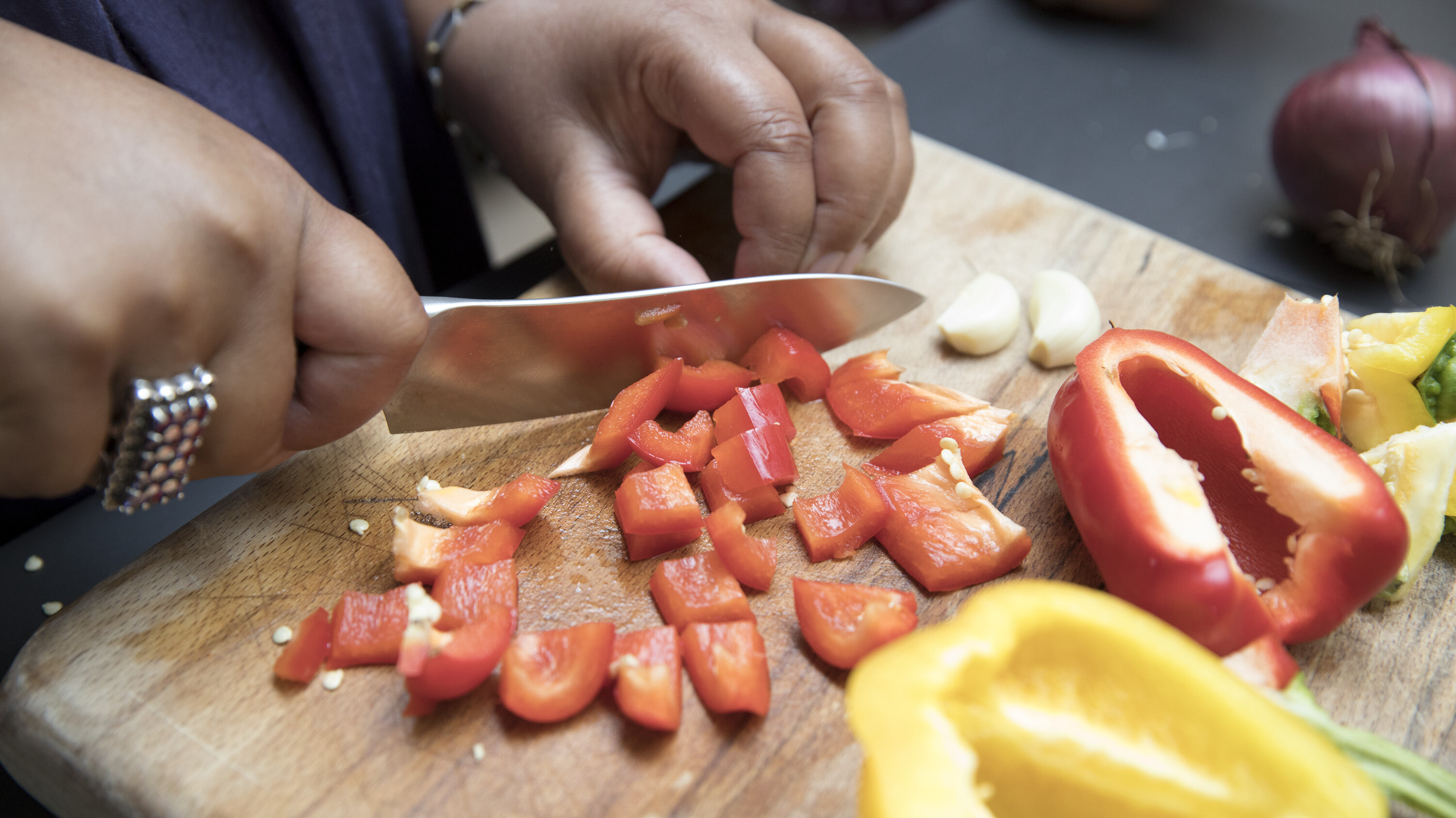 A close-up woman's hands chopping fresh vegetables