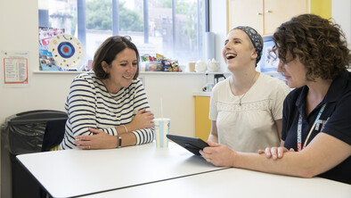 Community care coordinator project. Three women sat round a table looking at a tablet.