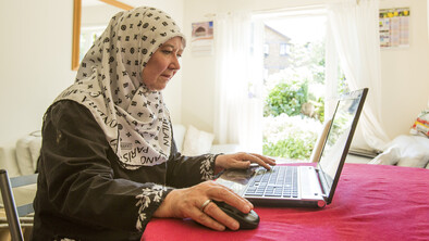 A woman uses a laptop on her dining room table.
