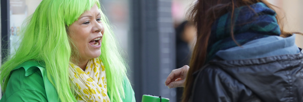 A woman with green hair collecting money for Macmillan on the street