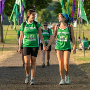 Two hikers in Macmillan t-shirts holding hands 