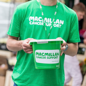 A person wearing a Macmillan t-shirt holding a fundraising bucket