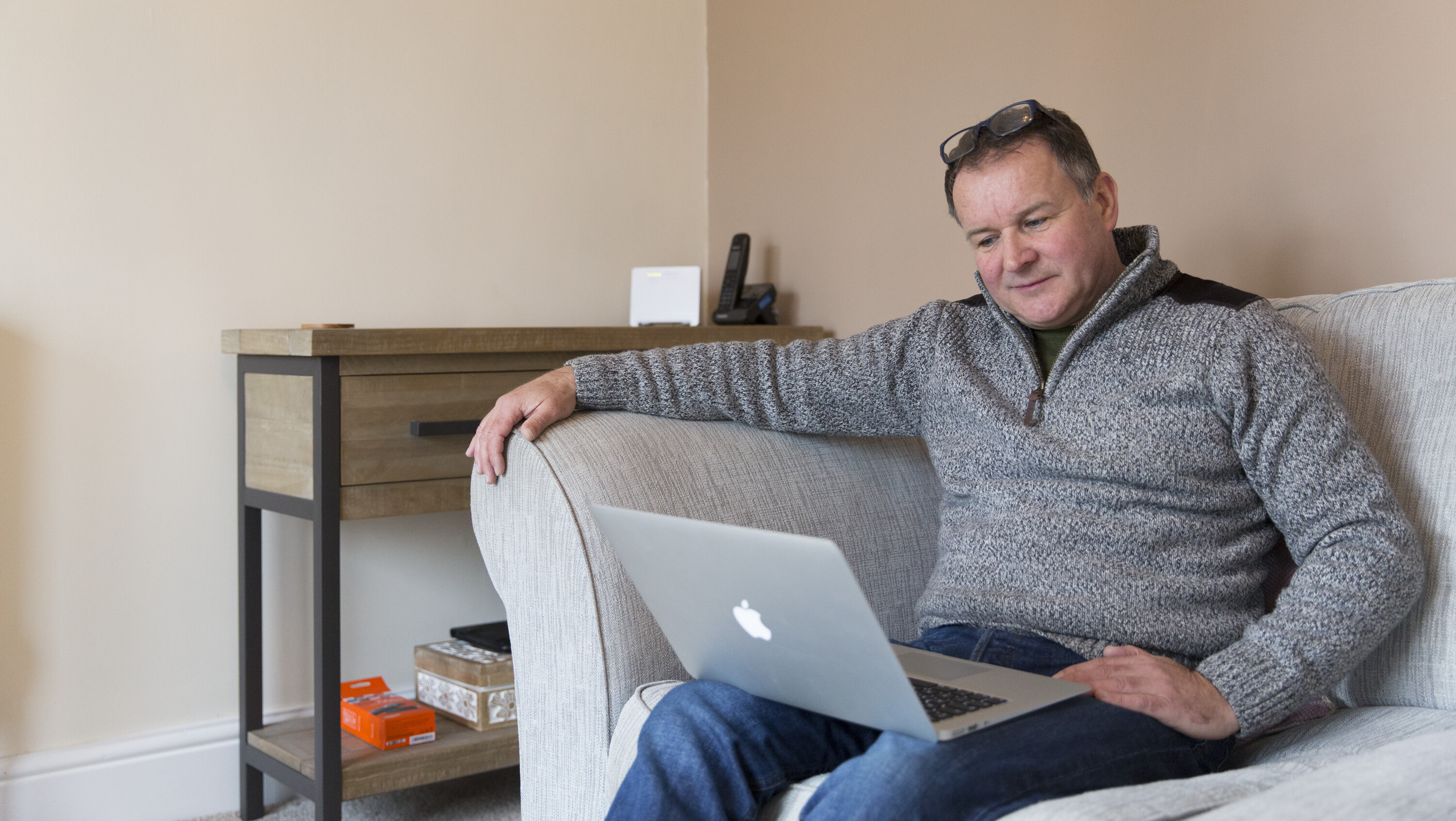 Man in grey jumper looking at laptop