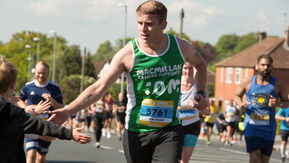 A Macmillan runner with his hand held out for a high five from a boy watching the race
