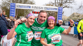 A man and 2 women stand together smiling at the finish line of a race.