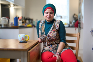 Woman sitting at kitchen table smiling while looking at camera.