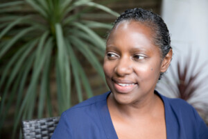 Woman in blue top sitting in chair and smiling.