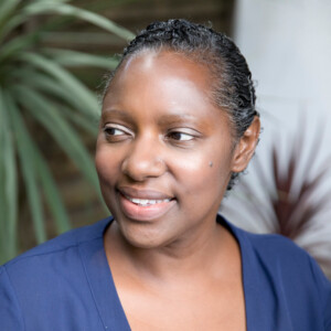 Woman in blue top sitting in chair and smiling.