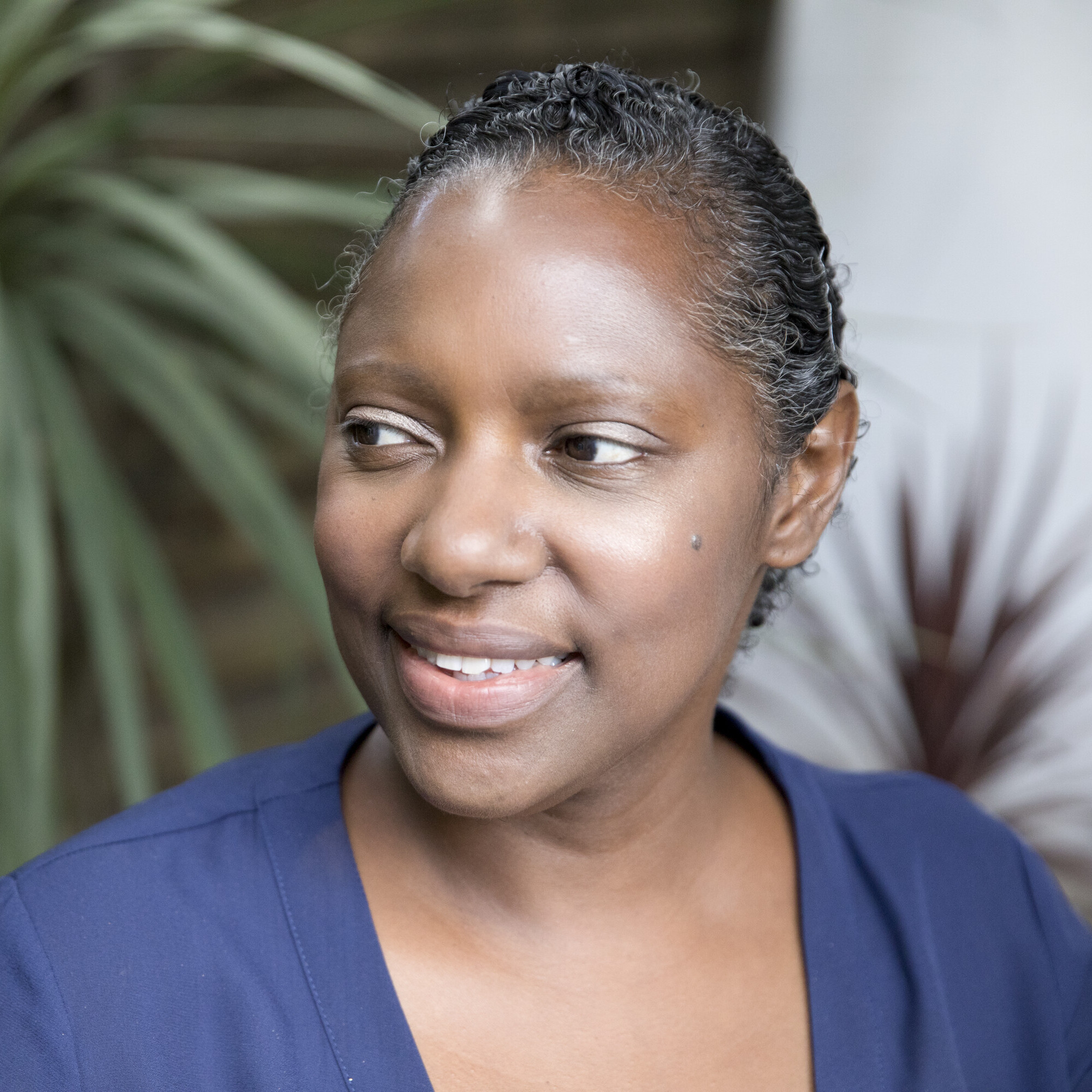 Woman in blue top sitting in chair and smiling.