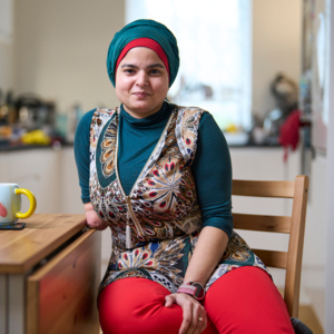 Woman sitting at kitchen table smiling while looking at camera.