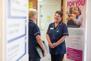 Two nurses talking and smiling in healthcare setting.