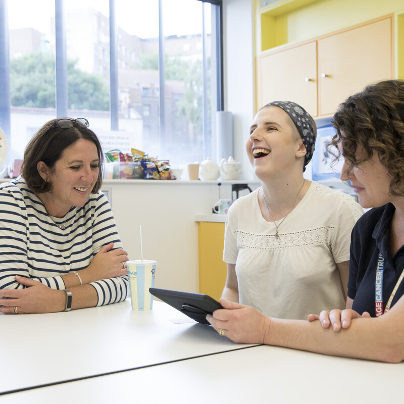 Community care coordinator project. Three women sat round a table looking at a tablet.