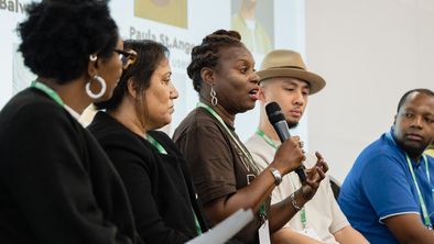 5 people of colour with lived experience of cancer talking on a panel at a conference