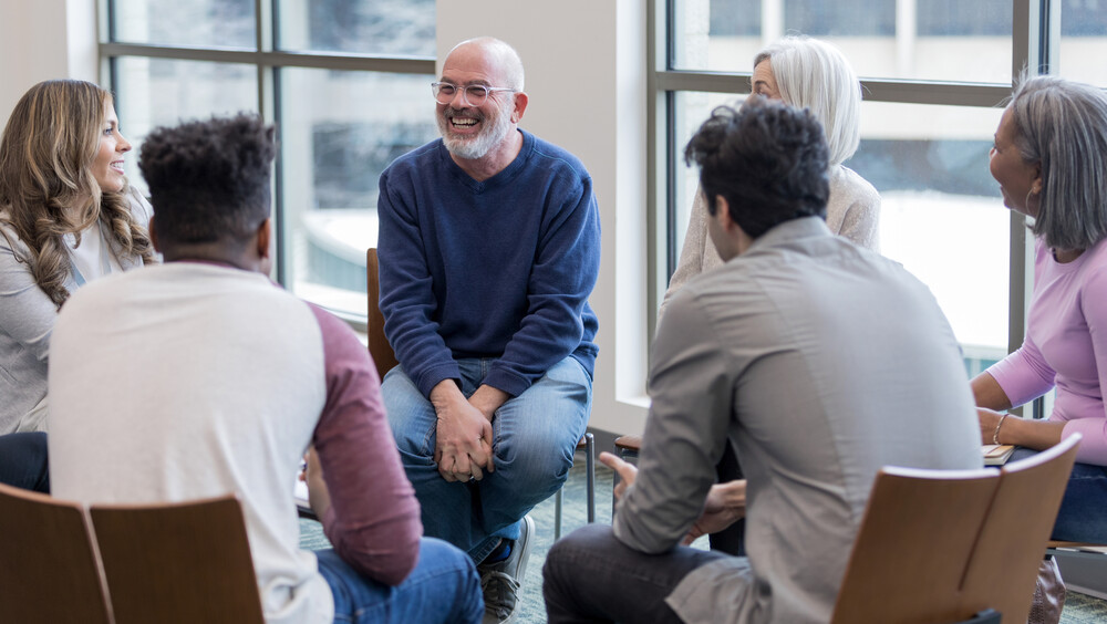 A group of adults sitting on chairs in a circle talking