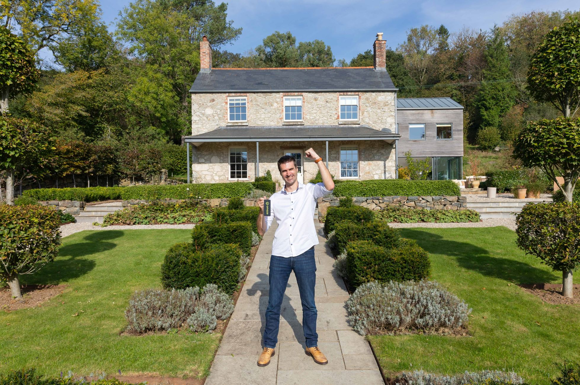 Omaze Million Pound House draw winner Simon Williams smiling while standing outside his new home in Devon