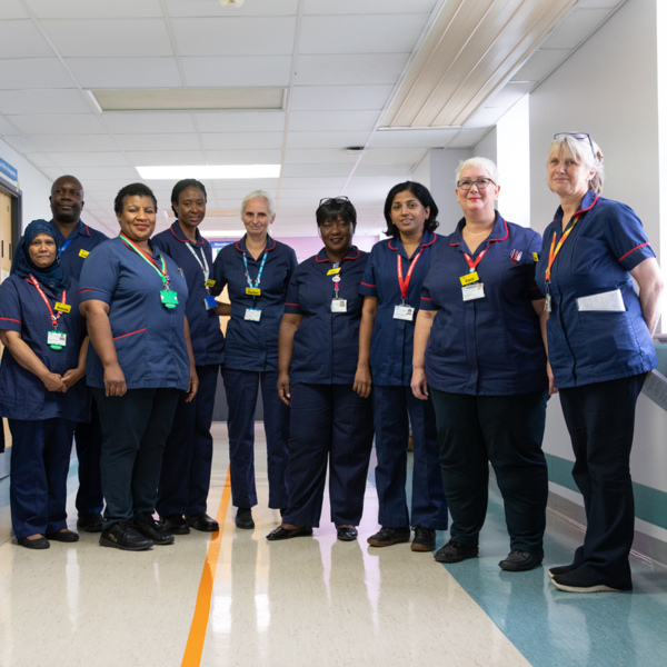A group of Macmillan nurses standing in a hallway. They are dressed in NHS nursing attire.