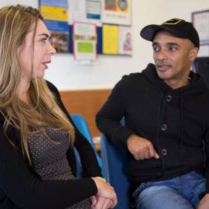Lloyd, wearing a baseball cap, sits talking to Emma, a Macmillan Benefits Advisor.