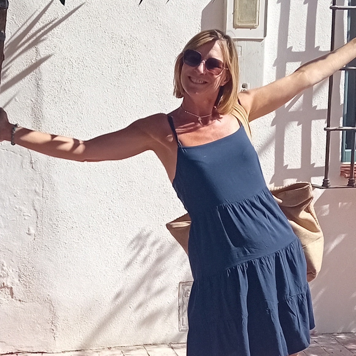 Natasha is a lady with short blonde hair in a blue summer dress.