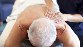A photo of someone laying face down on a massage table. They are having their back massaged.