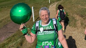 Laura is walking by the coast in a green Macmillan t-shirt.