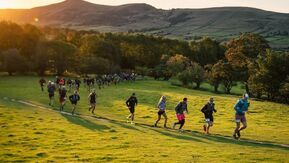 A line of people running through hilly countryside