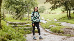 A woman in walking gear standing on a rural path smiling