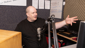 A man sitting behind a microphone in a radio studio