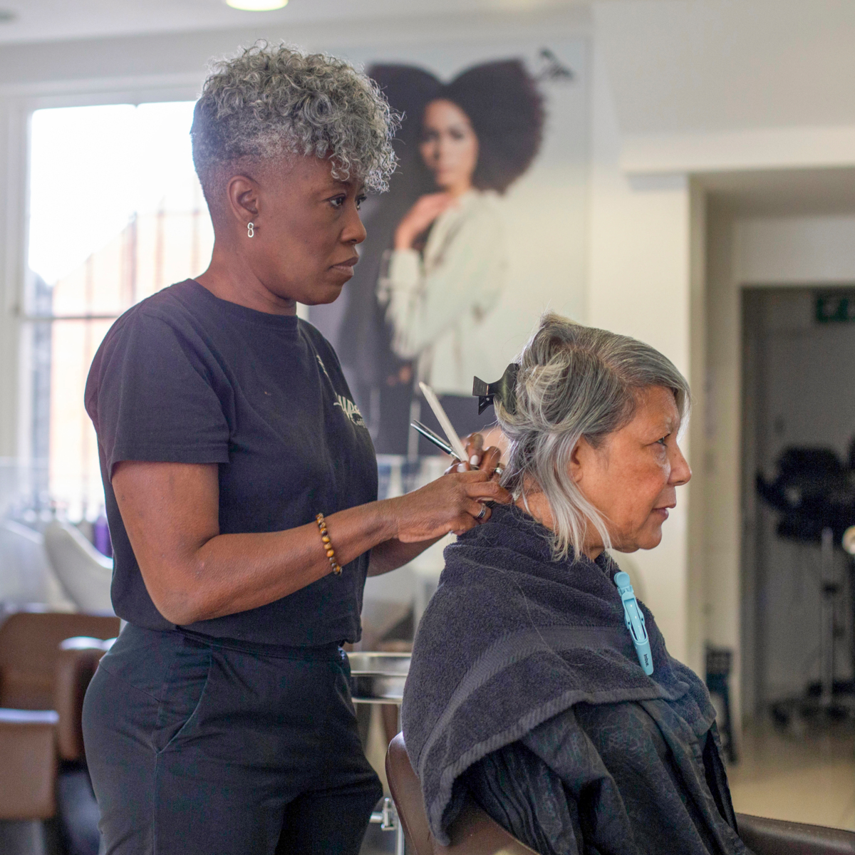 A hairdresser is standing behind her client