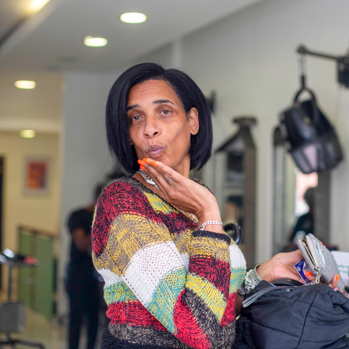 A woman in a hairdressers is blowing a kiss to the camera