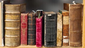 A video still from a YouTube video titled My Fight Back to Work. The video is part of Macmillan's Digital Storytelling project. The still shows a photo of old books that are viewed from their spines. 