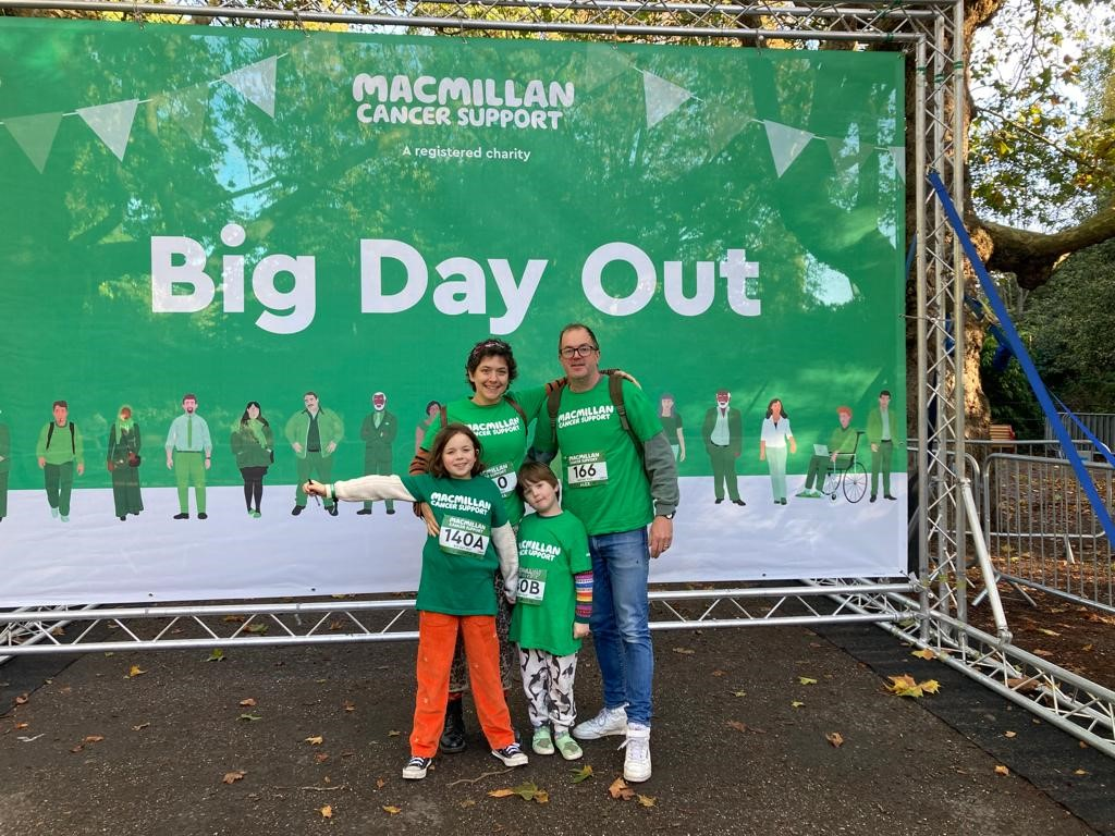 Two adults and two children wearing Macmillan t-shirts in front of a Big Day Out banner