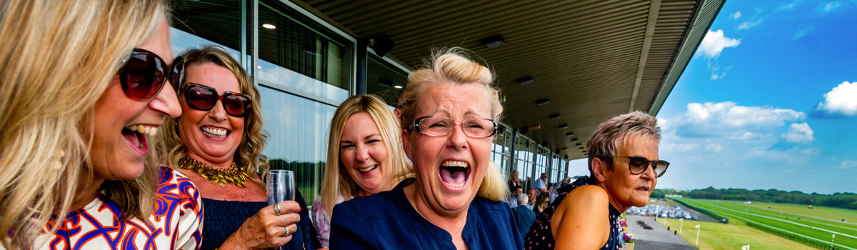 A photograph of revellers at the Macmillan Haydock Park Raceday in 2023.