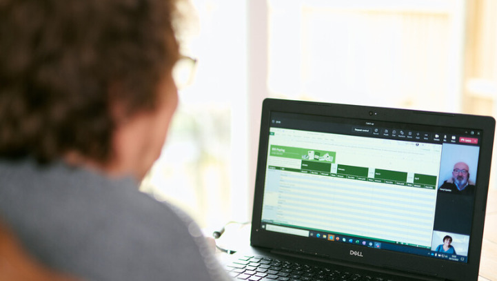 A woman sits at a desk with her laptop on a video call.