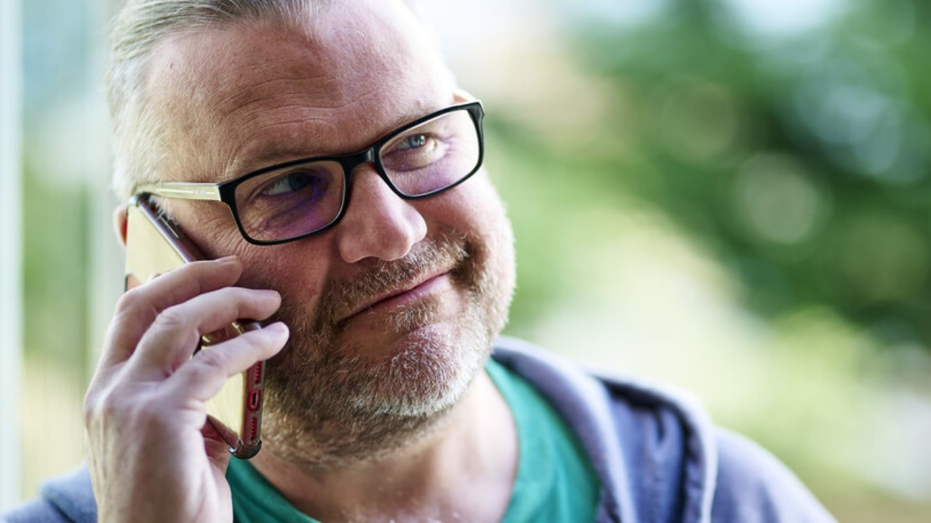 A man with beard speaking on the phone to Macmillan Buddies.