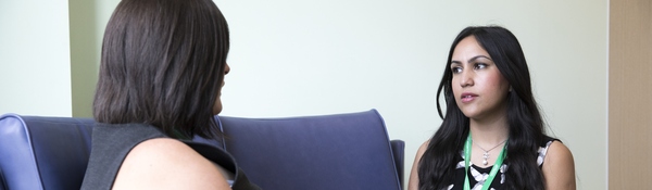 A Macmillan professional talking to a woman with her back to the camera on a sofa