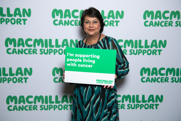 A south Asian lady with brown hair with a sign supporting people with cancer .