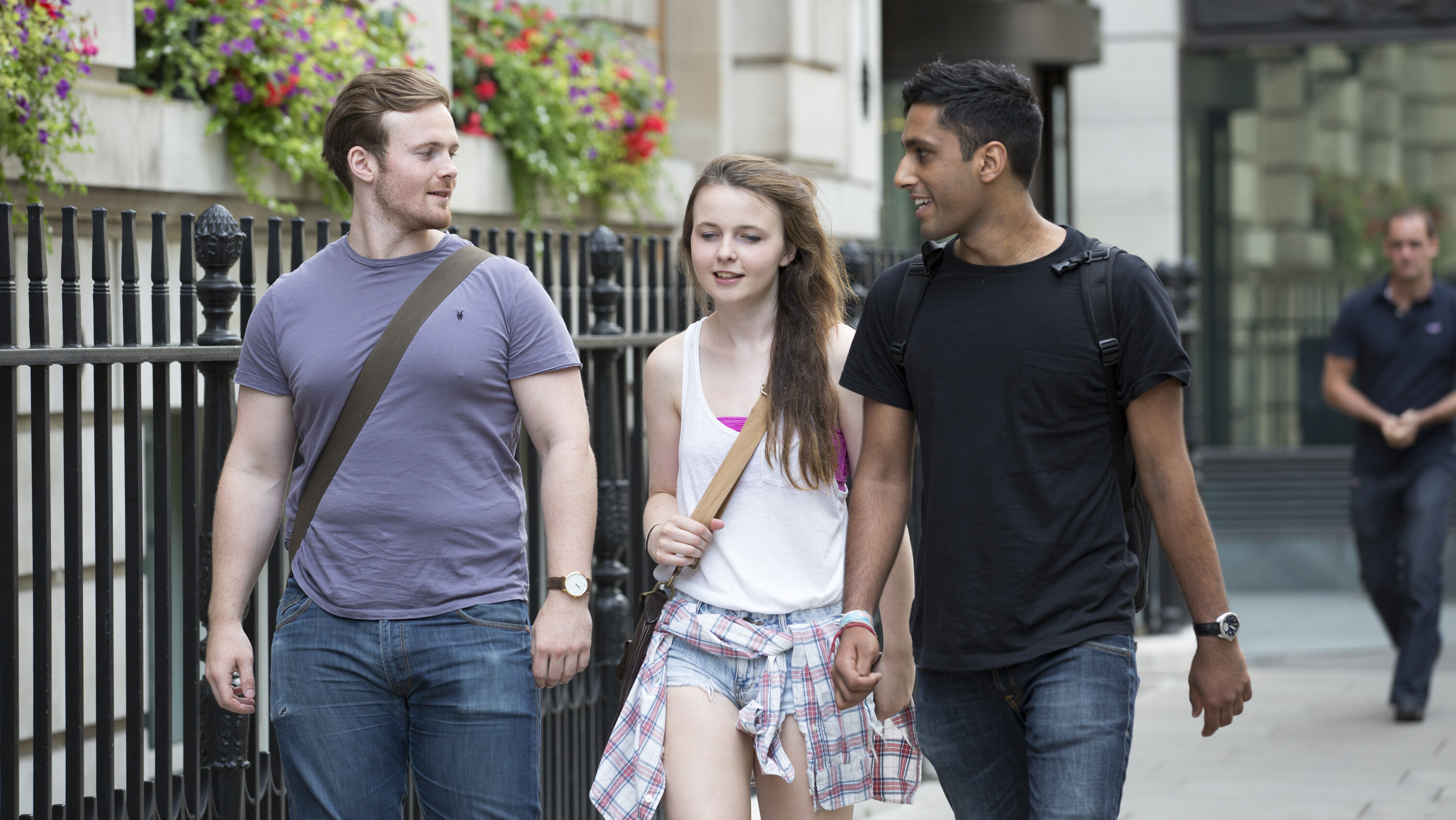 Three young people walking together along the pavement