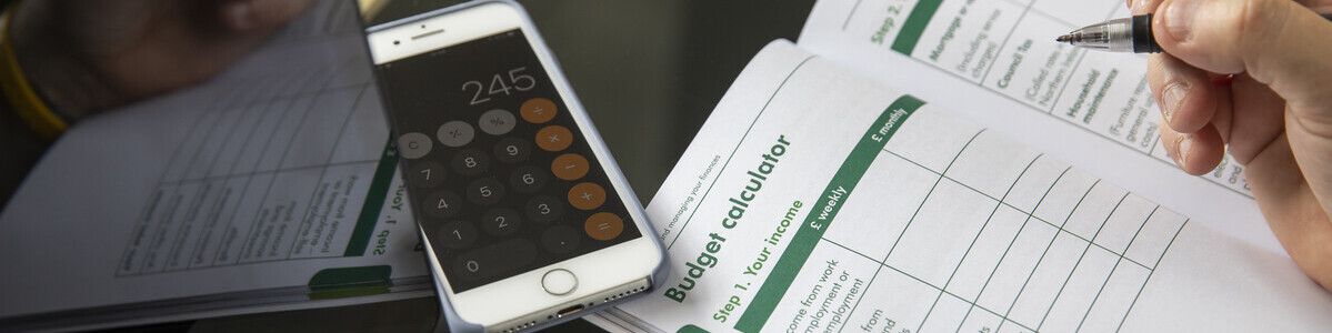 Image of a budget calculator booklet and phone showing the calculator app.