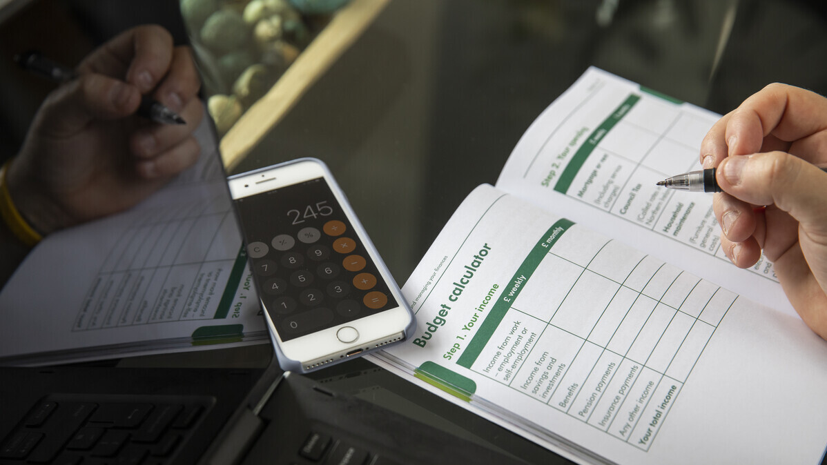 Image of a budget calculator booklet and phone showing the calculator app.